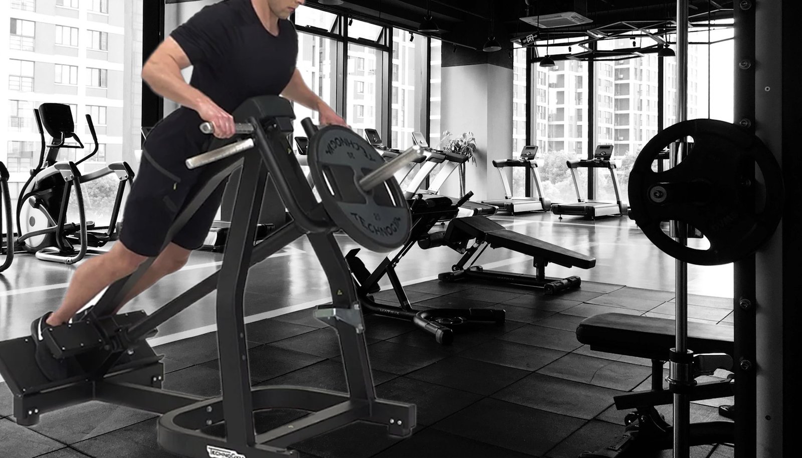 Person performing the T-bar row exercise, pulling a weighted T-bar toward their chest to engage back muscles in a gym.